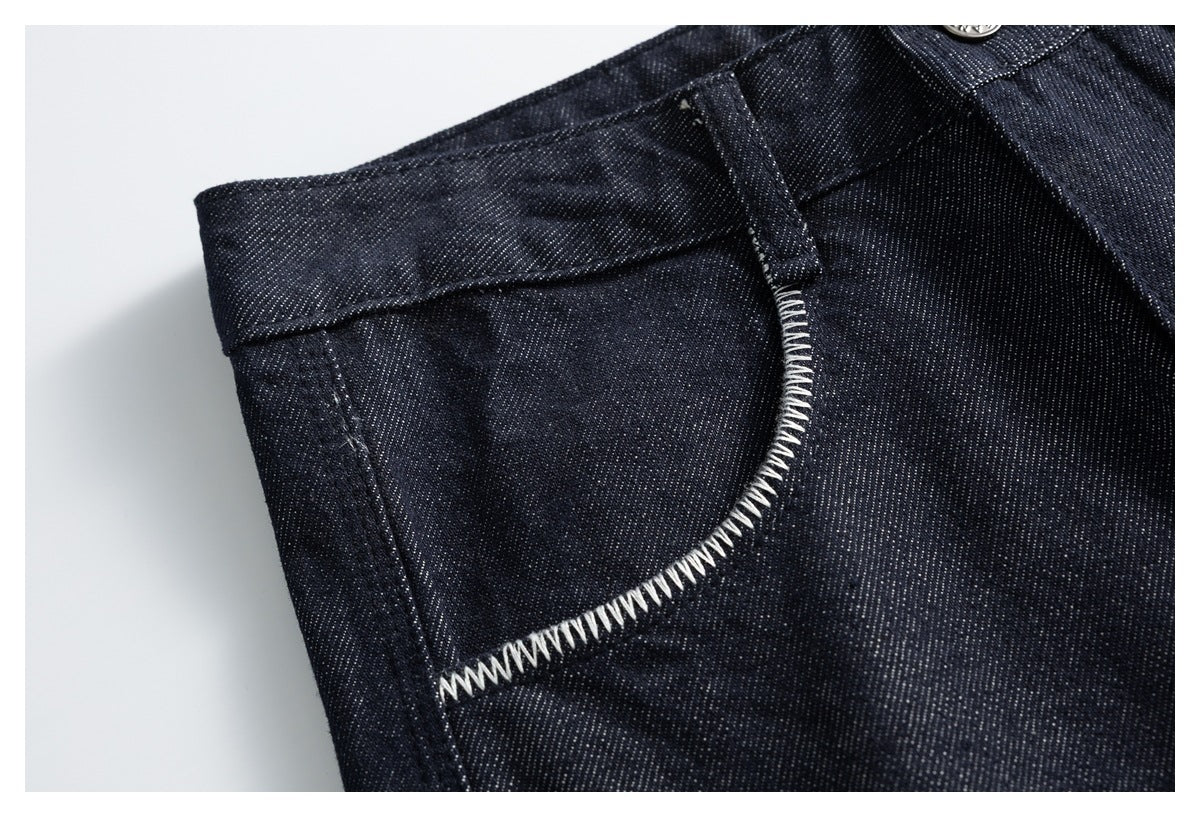 Close-up of a dark indigo denim trouser front pocket with prominent white zigzag stitching.