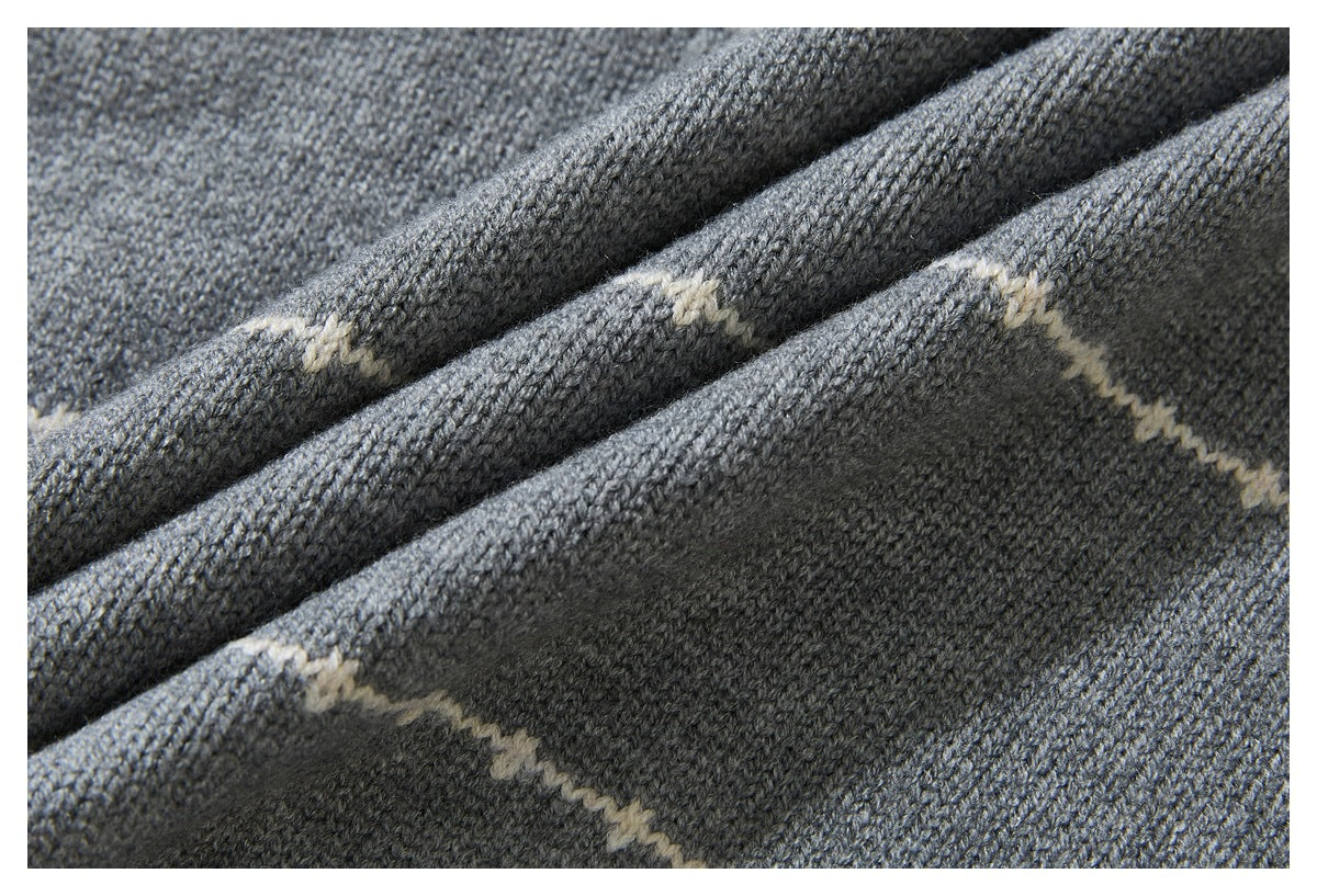 Macro view of gray sweater knit with cream stripe detailing and folded fabric.