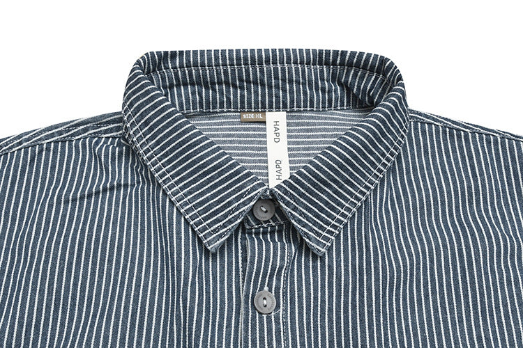Close-up of a dark vertically striped shirt collar, buttons, and sewn neck labels.