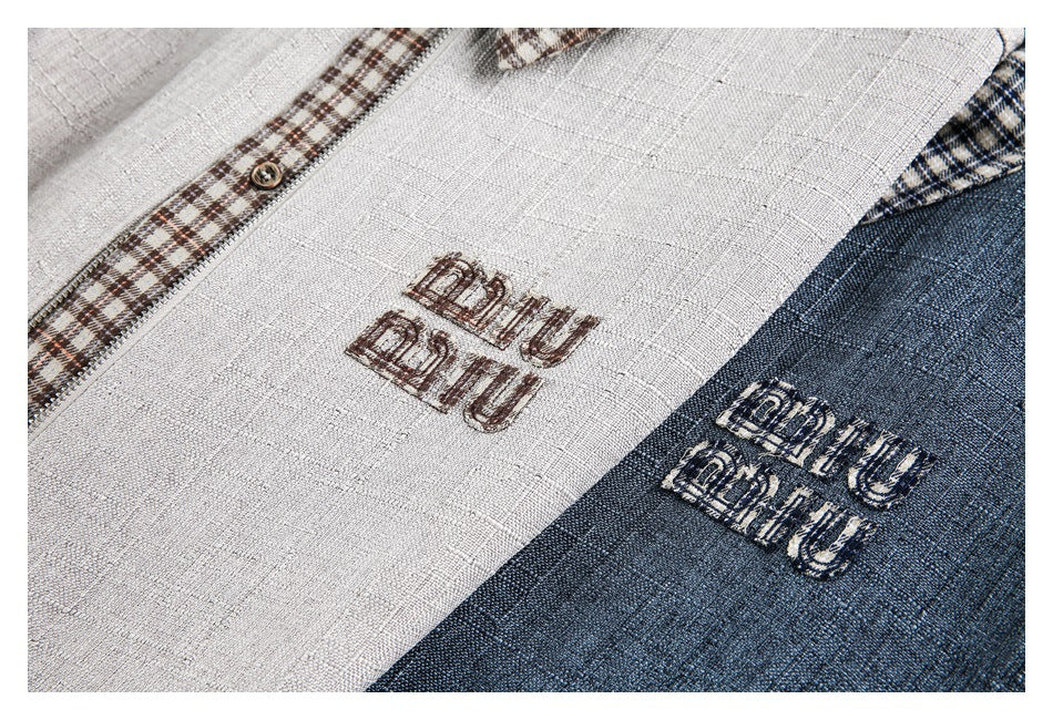 Close-up of cream and navy textured garment panels with embroidered lettering and a brown plaid trim.