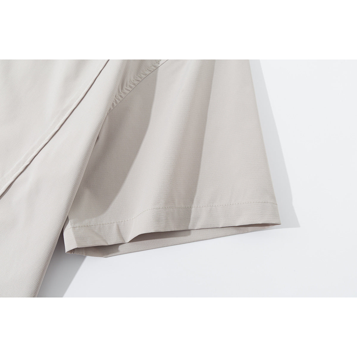 Close-up of the stitched hem on the short sleeve of a light beige shirt.