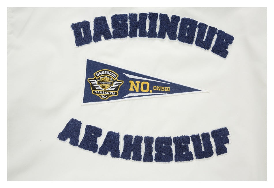Close-up of a white garment with navy chenille lettering and a triangular navy-and-yellow embroidered patch.
