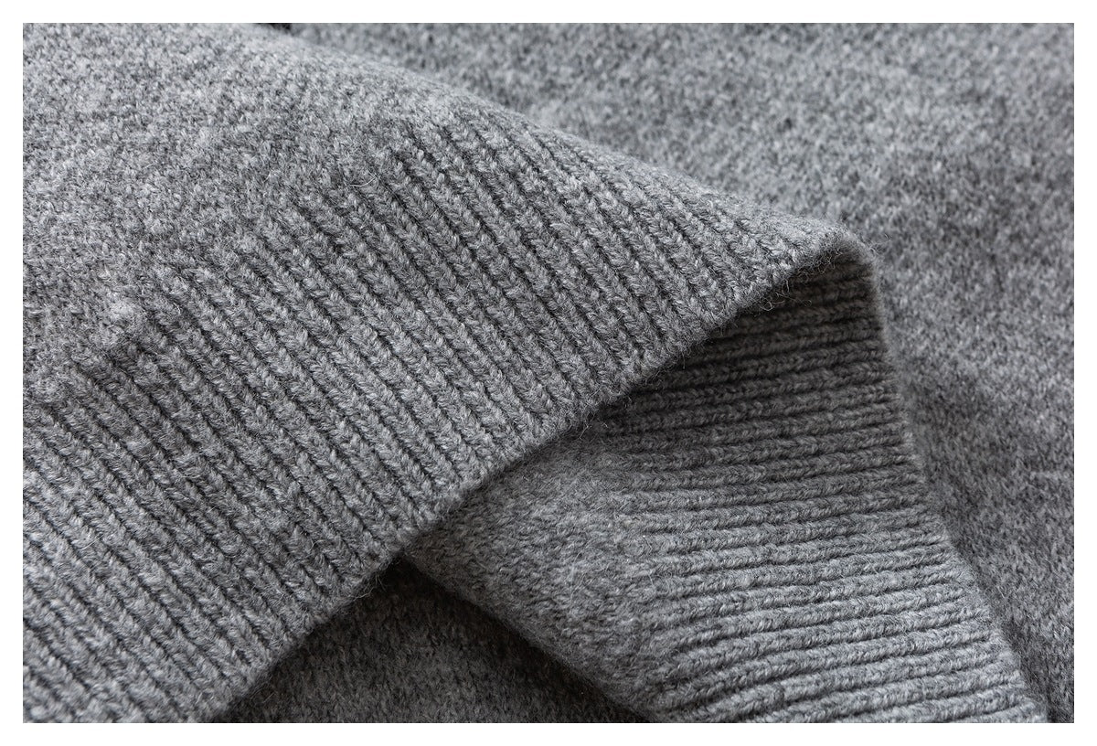 Close-up of a gray sweater sleeve folded to show its ribbed cuff and knit texture.