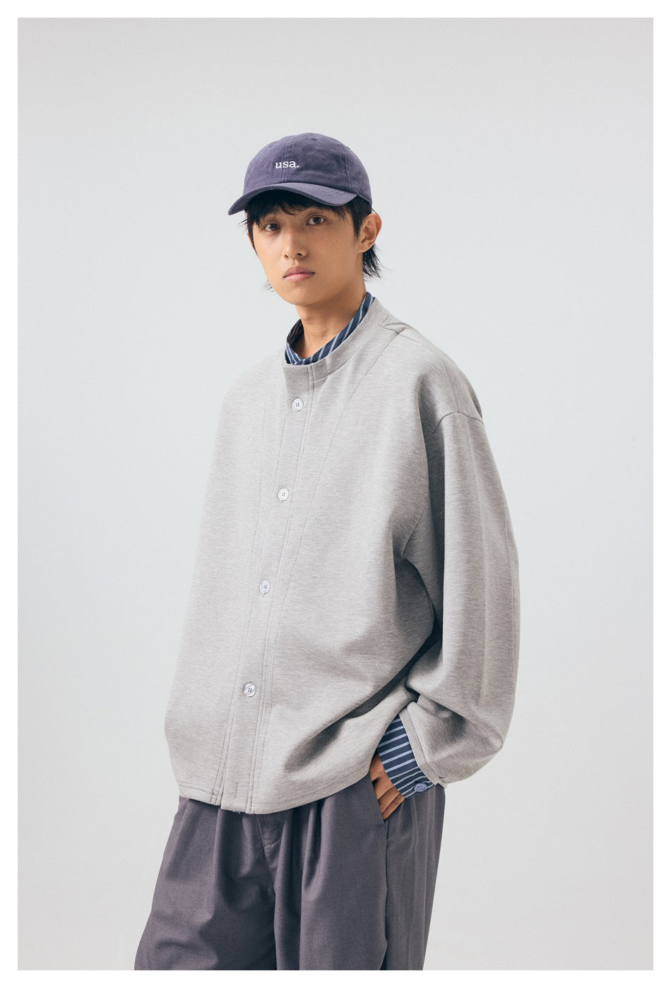 Model wearing the light gray button-front jacket and dark trousers, shown from the front at an angle.