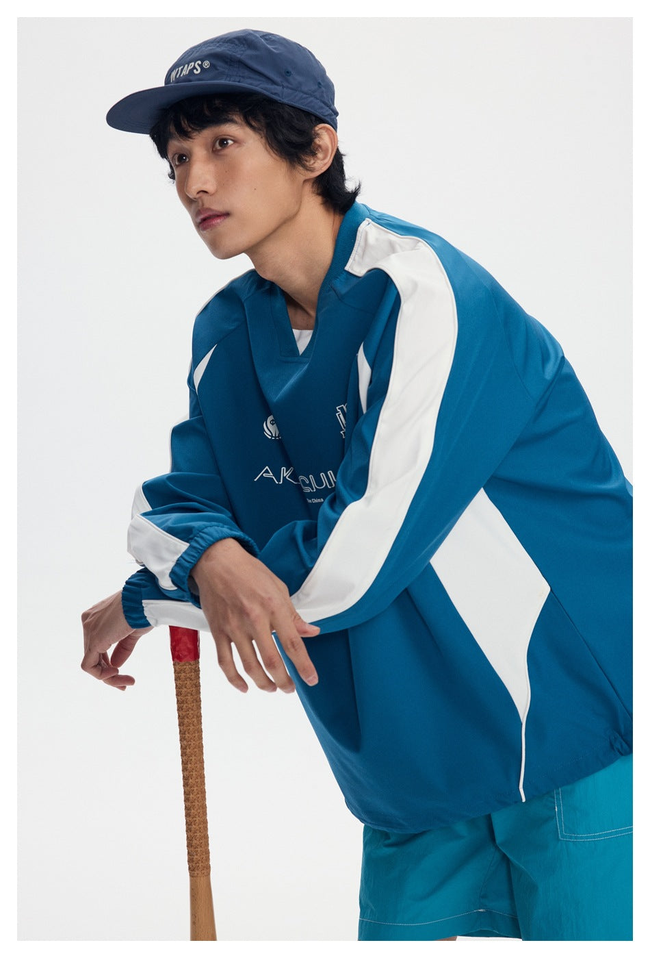 Close view of a model wearing a teal pullover with bold white sleeve and side panels.
