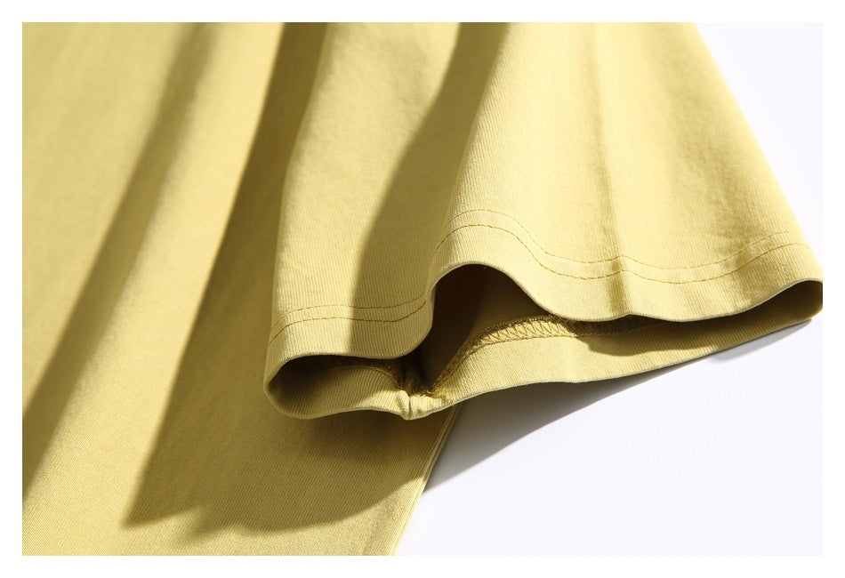 Close-up of the pale yellow T-shirt sleeve cuff with double stitching and the underside seam visible.