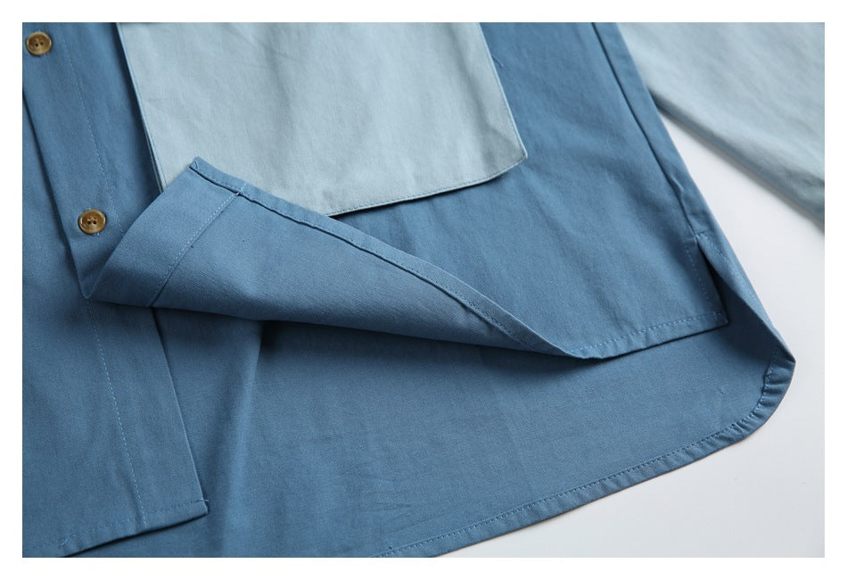 Close-up of a folded blue shirt panel with stitched edges, tan buttons, and a pale pocket above.