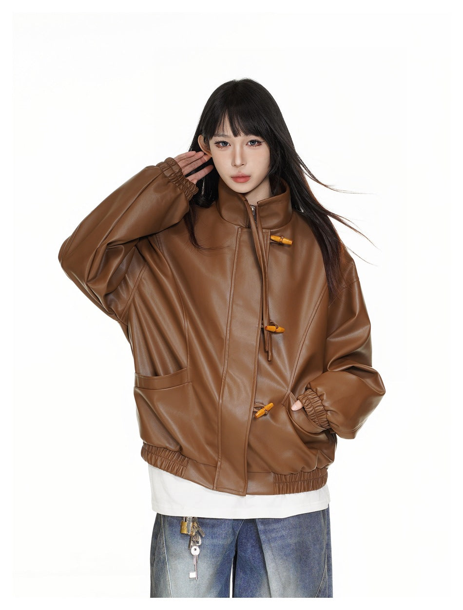 Closer front view of a brown high-collar jacket with toggle closures, gathered cuffs, and patch pockets, worn by a model.