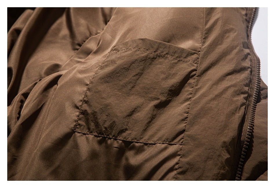 Close-up of a brown jacket showing a large stitched pocket and front zipper.