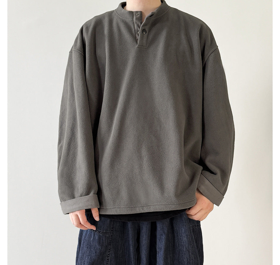 Model wearing gray fleece-like henley pullover with snap placket and rolled cuffs over dark jeans