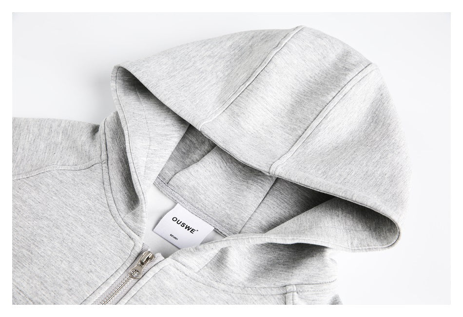 Close-up of a light gray heather zip-up hoodie hood, neckline, zipper, and sewn-in brand label.