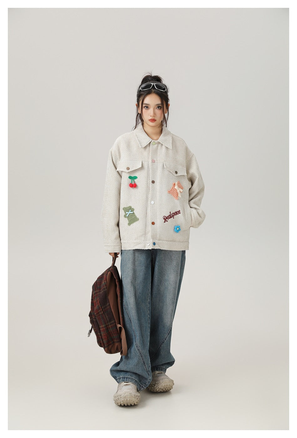 Front view of a model wearing a cream embroidered jacket with blue wide-leg jeans.