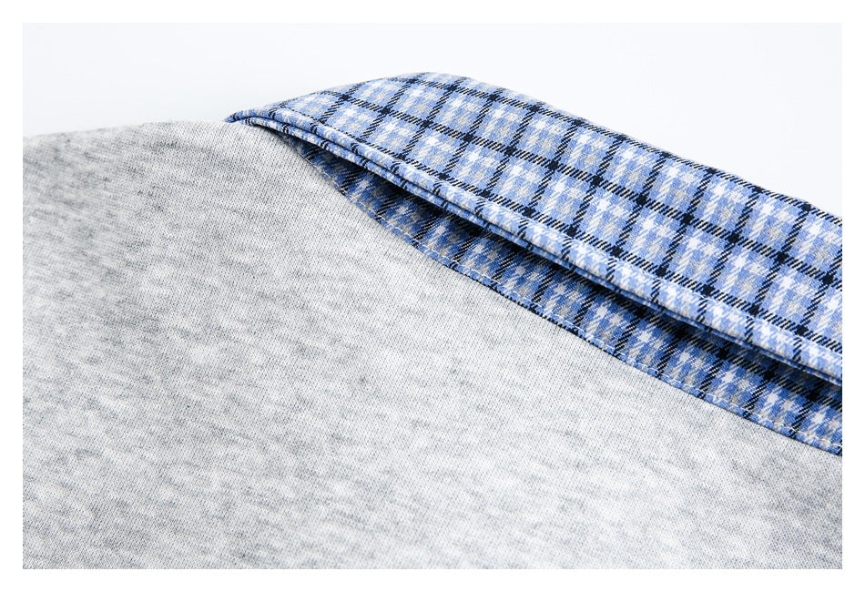 Close-up of the back of a blue plaid collar against light gray shirt fabric.