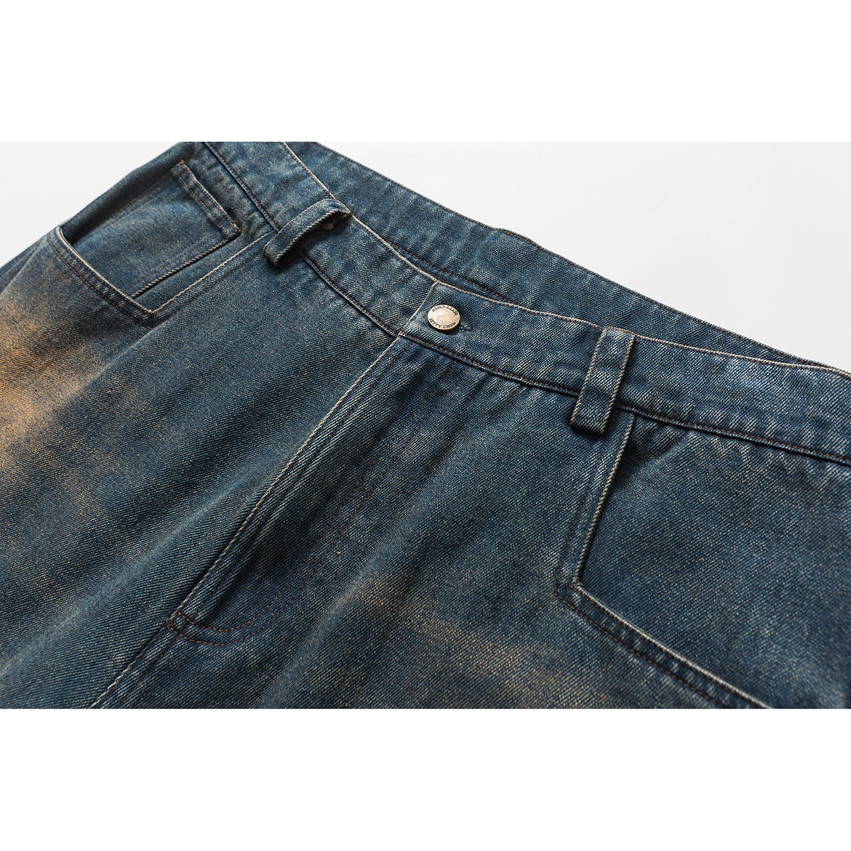 Close-up of blue distressed denim jeans showing the front waistband, button, belt loops and pockets.