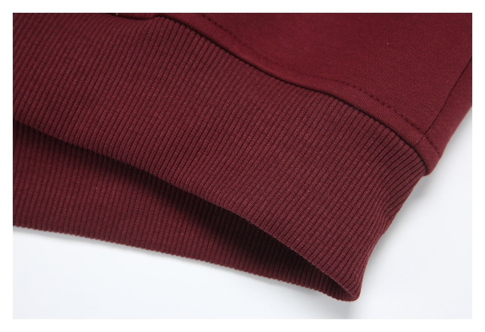 Close-up of the burgundy hoodie’s ribbed bottom hem and stitching.