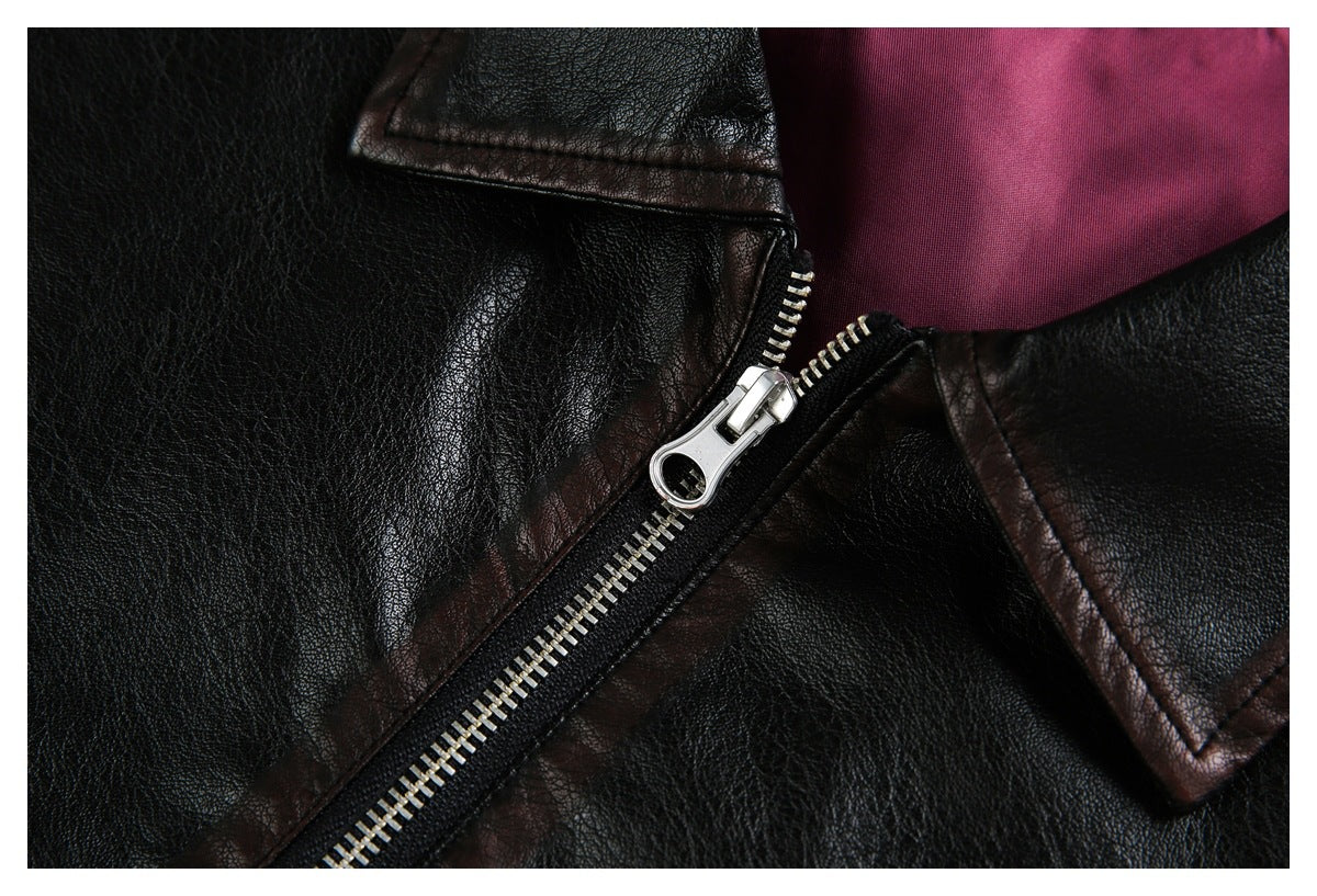 Close-up of a silver zipper and dark brown-trimmed lapel on a black jacket, with magenta lining visible.