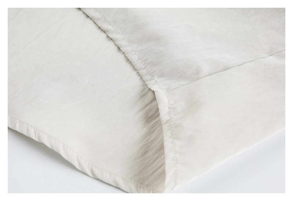 Close-up of stitching and a curved seam on light beige garment fabric.