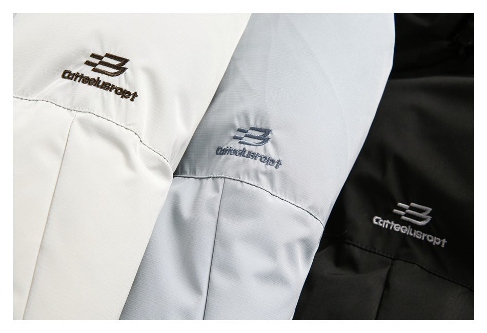 Close-up of embroidered logos on the chest areas of off-white, pale blue-gray, and black jackets.