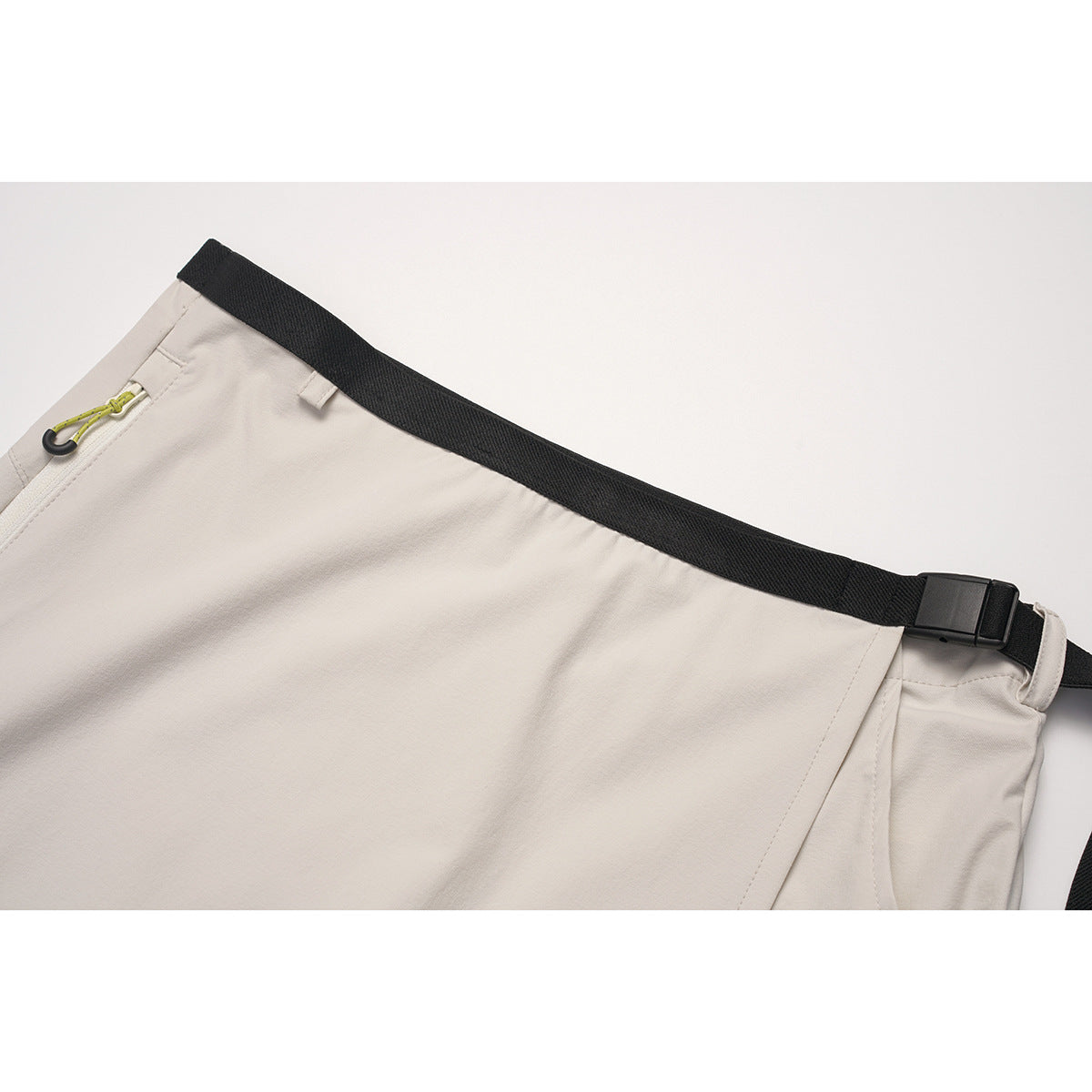 Close-up of a light beige skirt waistband with a black adjustable belt and zip pocket.