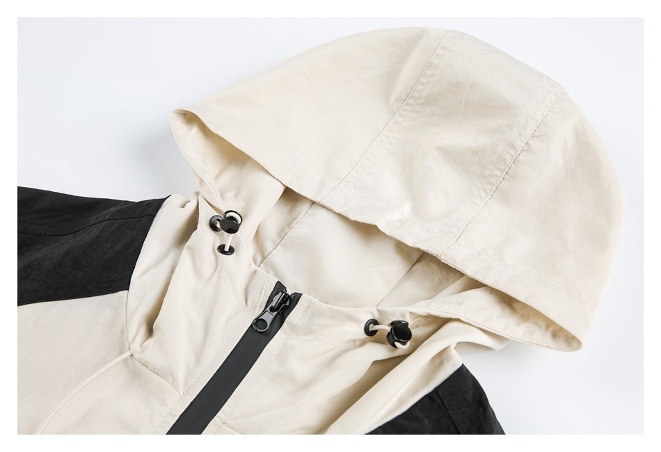 Close-up of a cream hooded jacket showing its hood, black front zipper, and adjustable toggles.