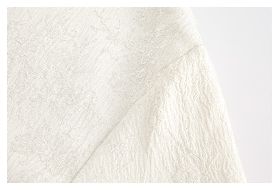 Close-up of ivory floral-textured fabric with a curved seam.