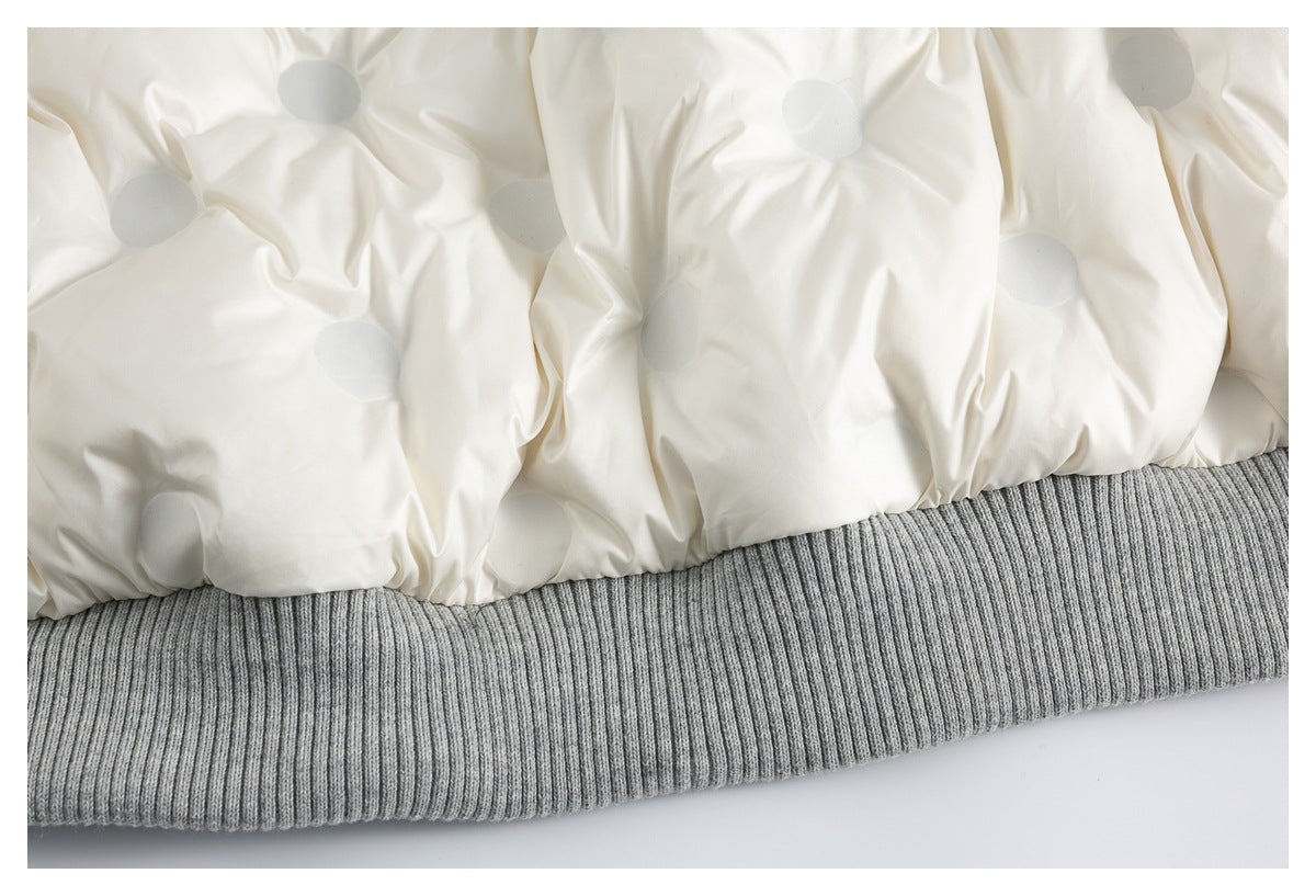 Close-up of a cream, lightly dotted jacket lining above a wide gray ribbed hem.