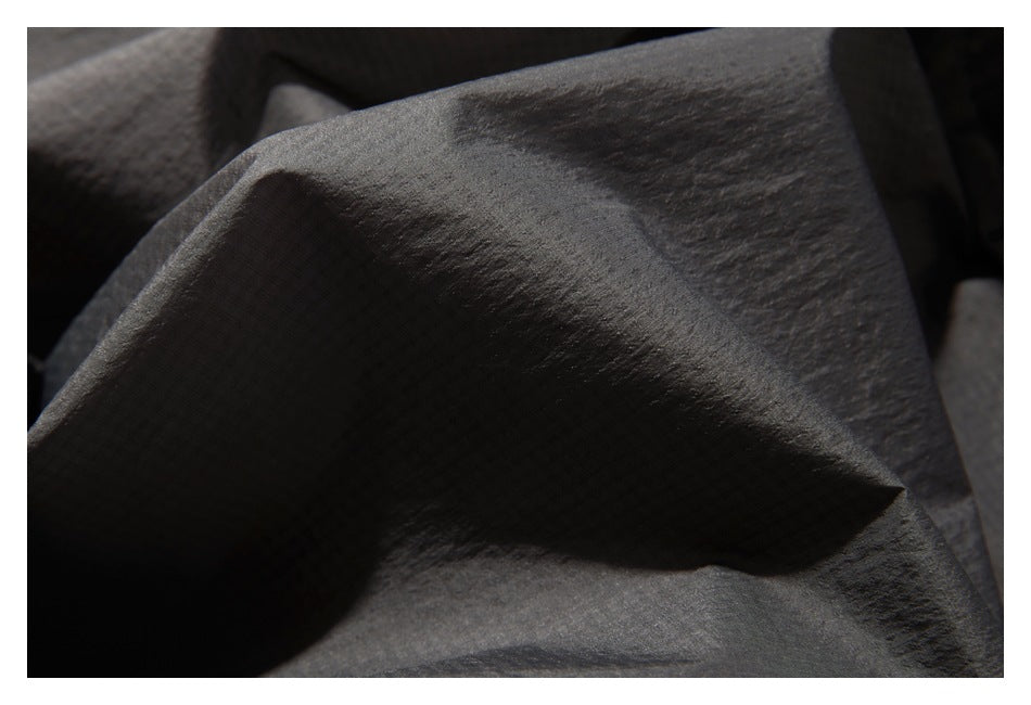 Close-up of dark charcoal fabric showing its fine textured surface and soft folds.