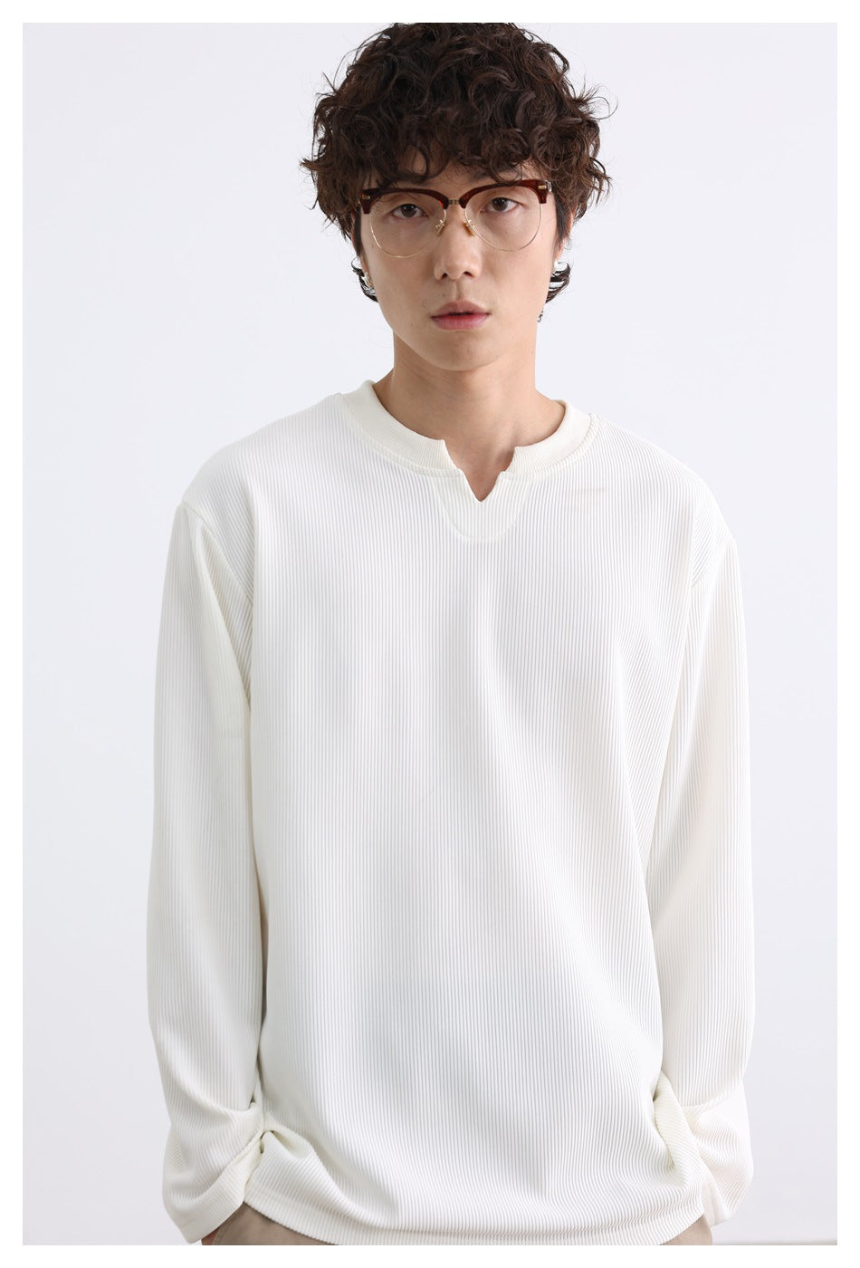 Close view of a model wearing an ivory ribbed long-sleeve top with a notched crew neckline.