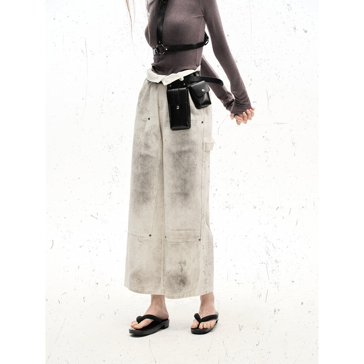 Front view of a model wearing off-white mottled wide-leg utility pants with large pockets and a black belt pouch.