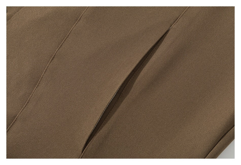 Close-up of a narrow pocket opening and stitched panels on the brown garment.