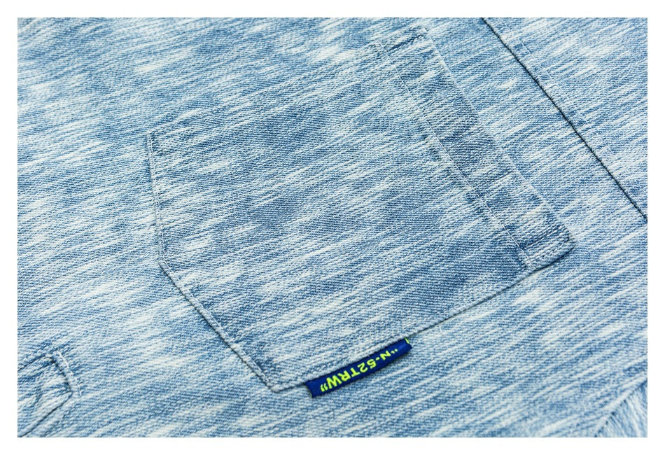 Close-up of a square patch pocket and small woven brand tab on the light blue patterned jacket.