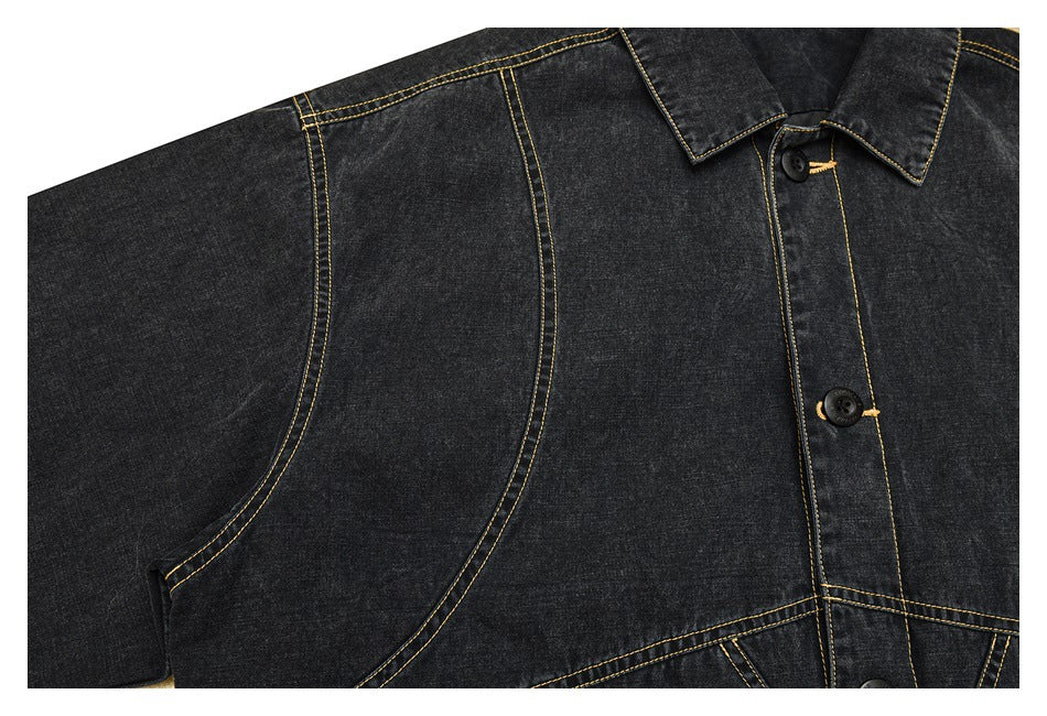 Close-up of the charcoal denim jacket's side panel, curved seam and button placket with yellow stitching.