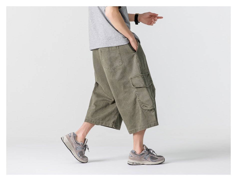 Side view of a model wearing dark olive knee-length cargo shorts with large flap pockets.