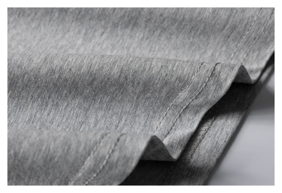 Close-up of the folded hem and stitching on a heather gray T-shirt.