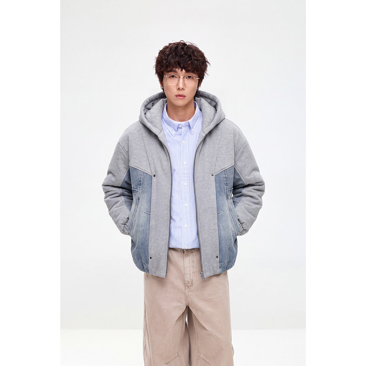 Model wearing a gray hooded zip jacket with blue denim panels, shown from the front.