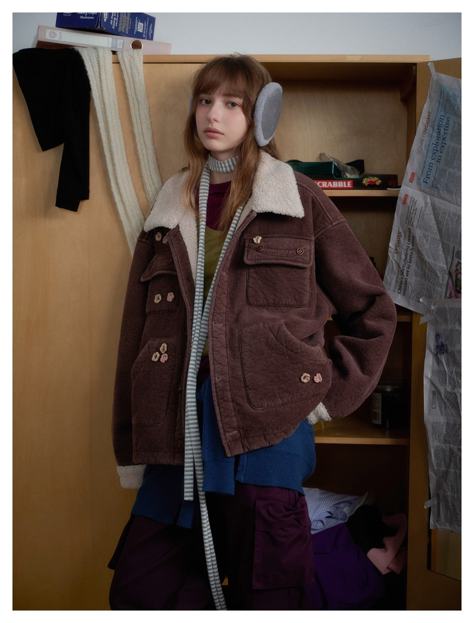 Three-quarter view of a model wearing a brown corduroy jacket with a cream shearling collar and cuffs and flower appliqués.