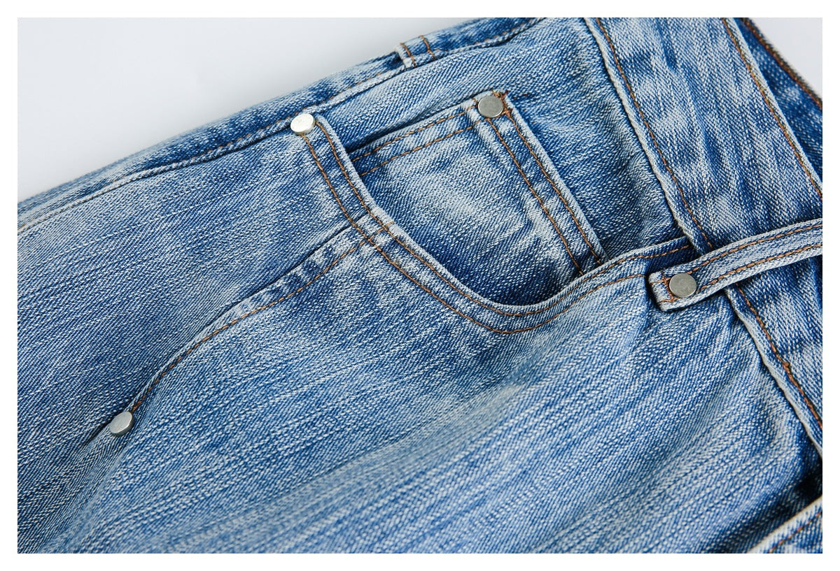 Close-up of a curved front pocket, coin pocket, rivets, and contrast stitching on blue jeans.