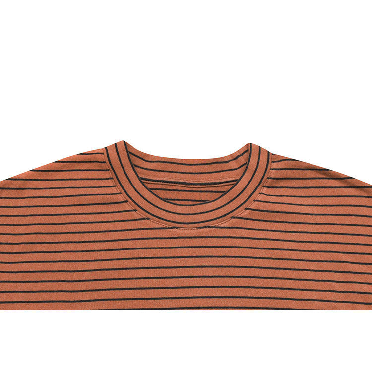 Close-up of a rust-orange shirt with thin black horizontal stripes and a double-stitched crew neckline.