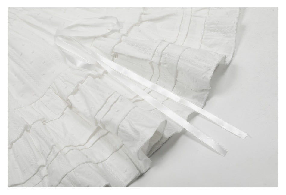 Close-up of a white tiered ruffle skirt with long white ribbon ties.
