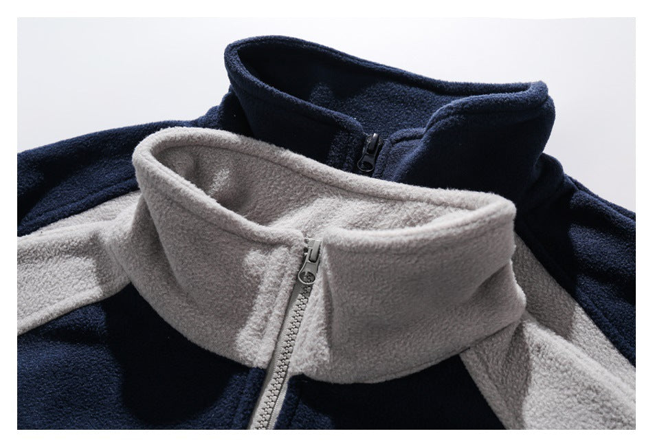 Close-up of two fleece pullovers highlighting their tall collars and front zippers in navy and light gray.