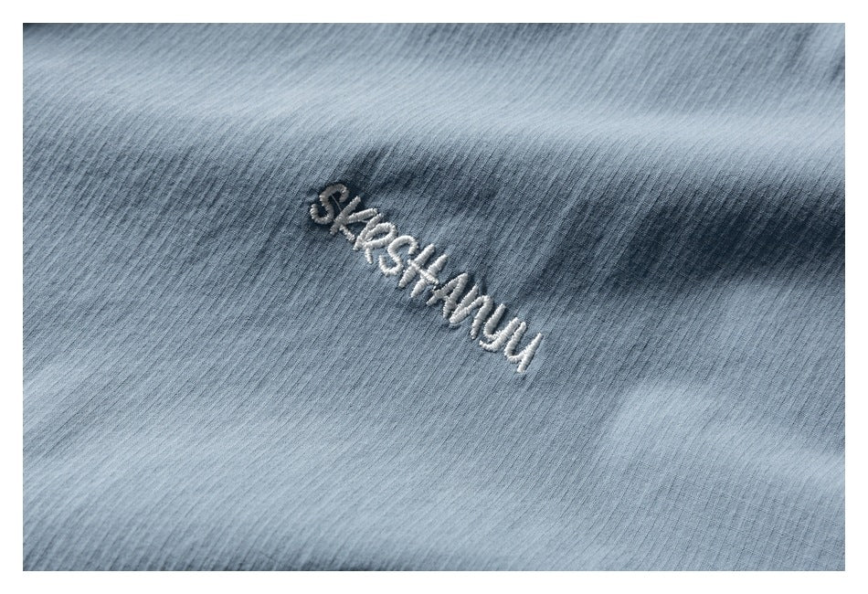 Close-up of white embroidered lettering on light blue fabric.