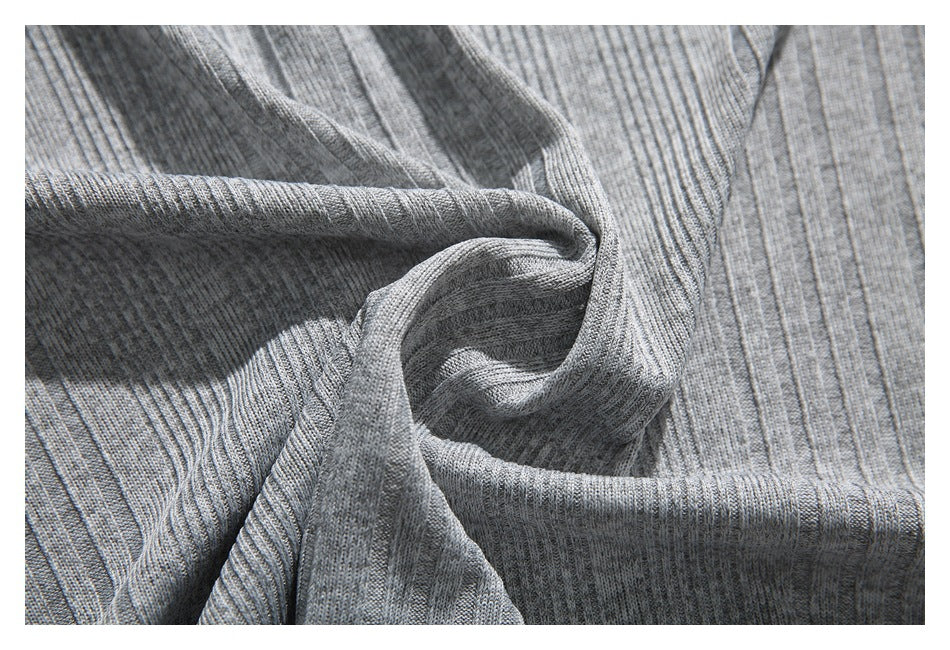Close-up of gray ribbed knit fabric draped into folds, showing its vertical texture.