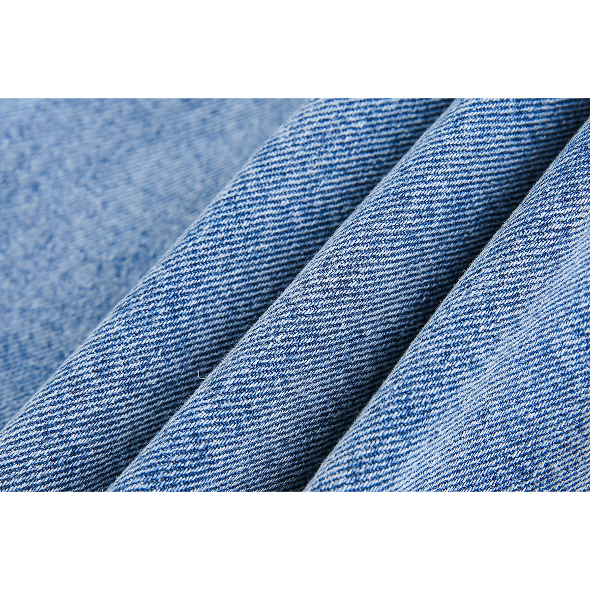 Macro view of the blue diagonal weave and folds of denim fabric.