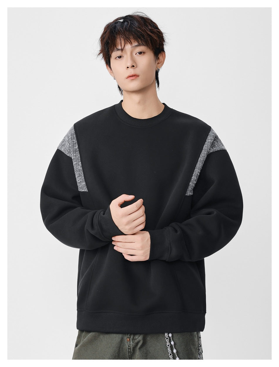 Front view of a model wearing a black crewneck sweatshirt with gray textured shoulder panels.