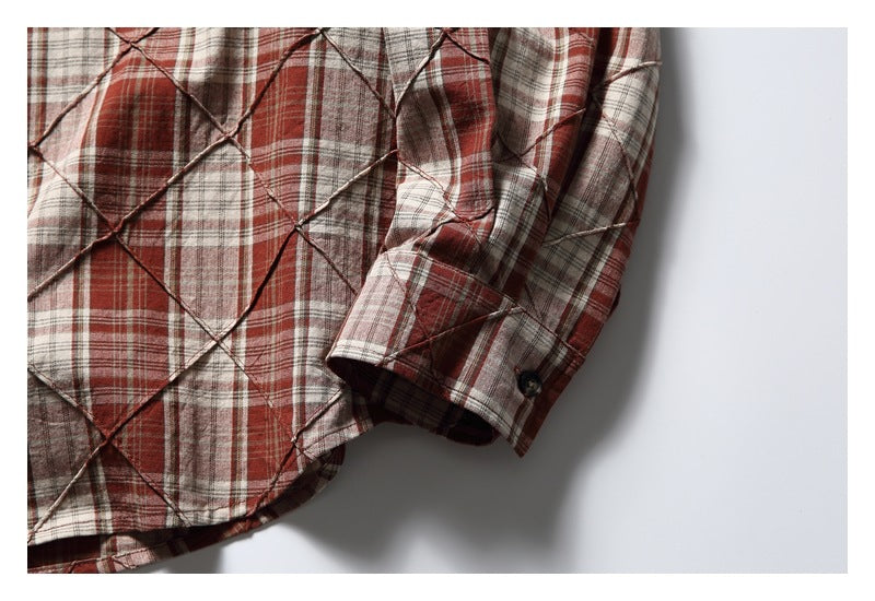 Close-up of the plaid shirt sleeve and buttoned cuff, showing layered diamond-shaped fabric panels.