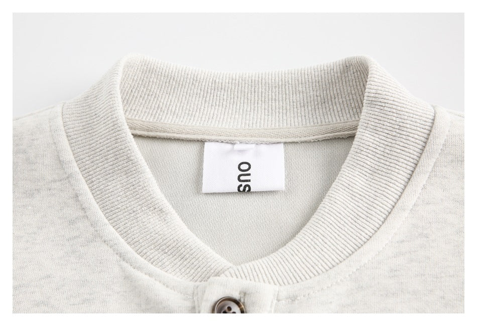Close-up of a light gray sweatshirt's ribbed collar and sewn-in neck label.