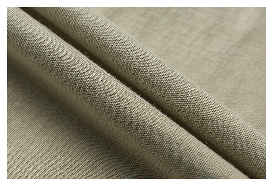 Close-up of muted beige knit fabric draped in soft folds, showing its fine ribbed texture.