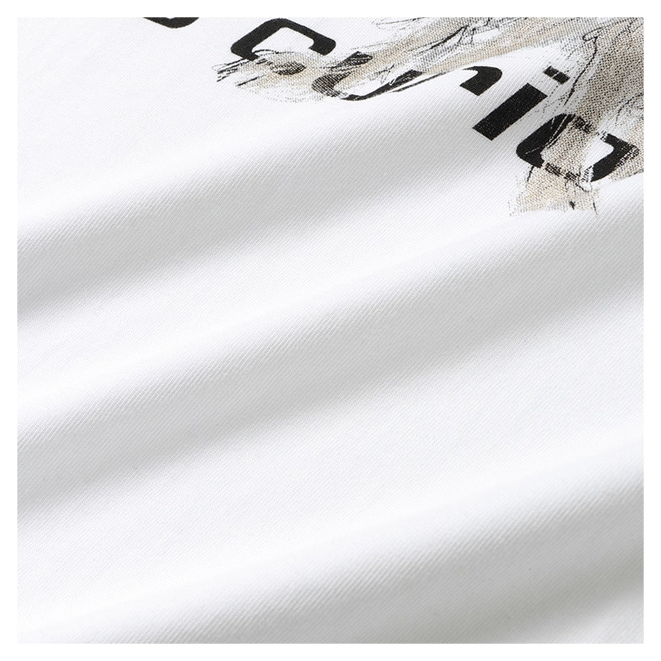 Close-up of white shirt fabric with part of a black-and-gray graphic and cropped black lettering.