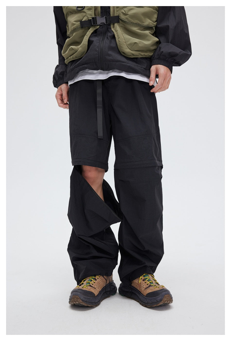 Model wearing black convertible pants; one lower leg is opened to reveal the shorts layer beneath.