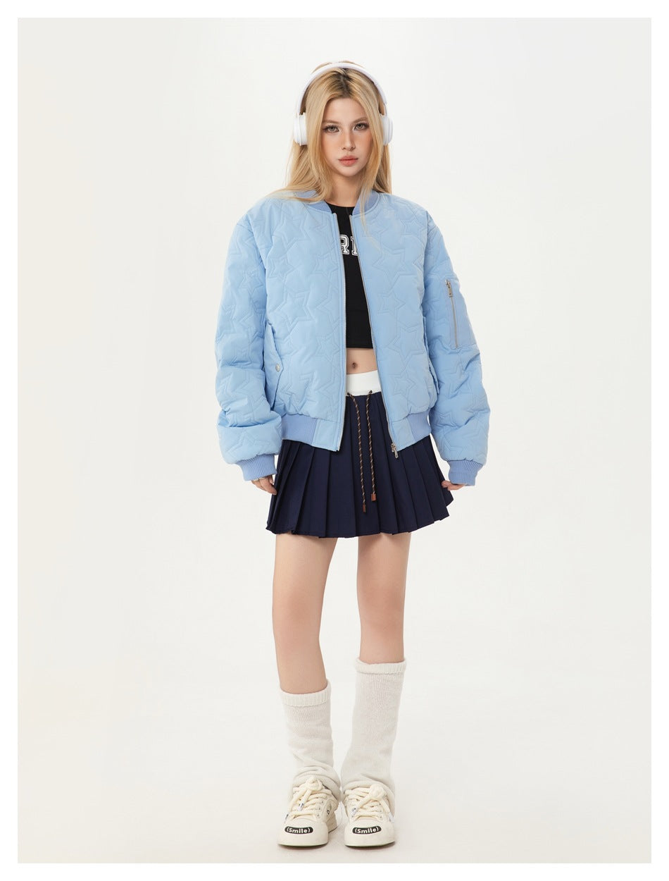 Model wearing the light blue quilted star-pattern bomber jacket open over a black top and navy pleated mini skirt